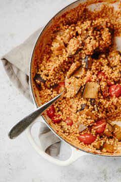 A dish of pearl couscous with tomatoes and aubergine.