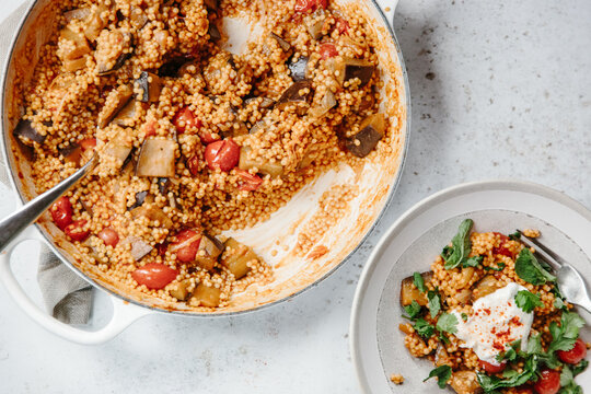 A dish of pearl couscous with tomatoes and aubergine.