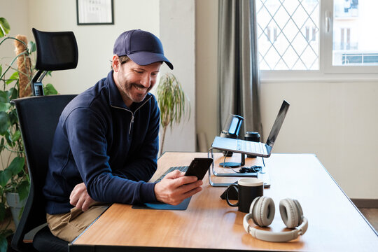 Smiling man browsing smartphone at workplace