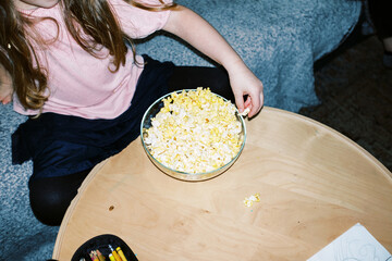 little girl eating popcorn at home in living room