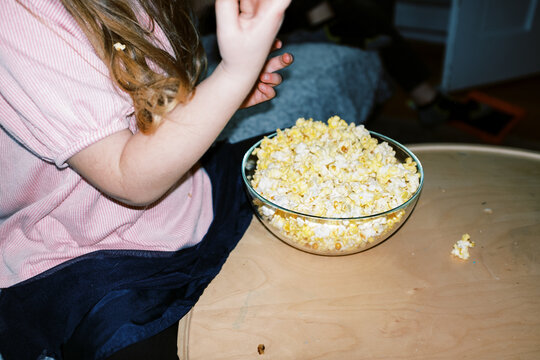 little girl eating popcorn at home in living room
