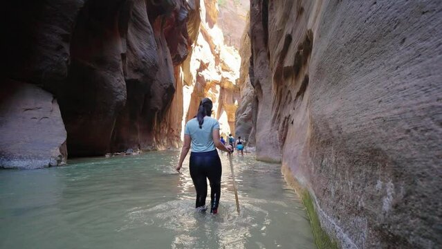 Young Woman on Hiking Adventure in the Narrows Slot Canyon in Zions, Utah
