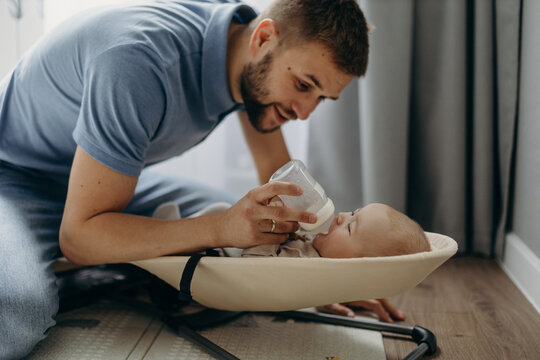 Father feeding newborn baby with milk from bottle