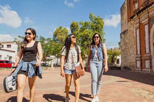 Young independent women on vacation. Group of three tourist friends smiling, walking down the street enjoying, getting to know and exploring the city.  Concept of travel, tourism 