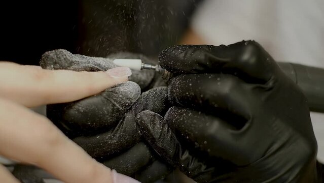 Manicurist works with a milling cutter close-up, nail extension. Removing material
