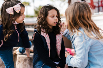 Girl applying lip gloss on friends lips