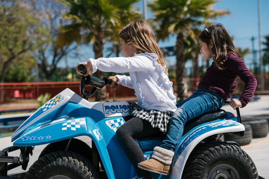 Girls driving quad bike on playground