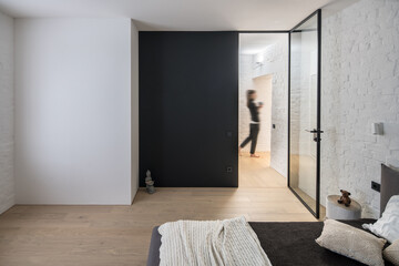 Loft style bedroom with modern light bed and unknown woman at the hall