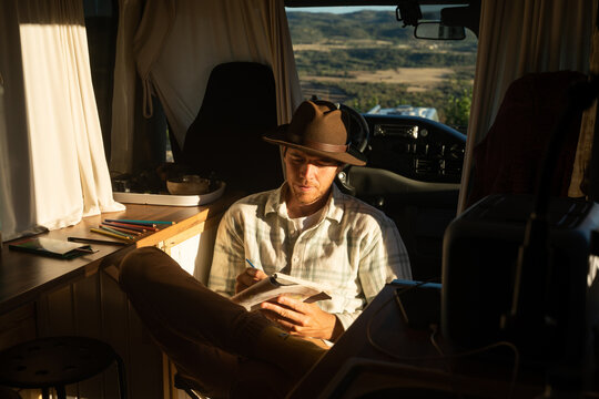 Man drawing in notebook inside camper van caravan