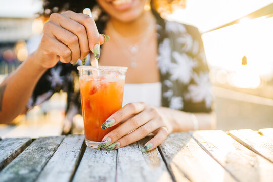 Crop female mixing fresh drink in glass