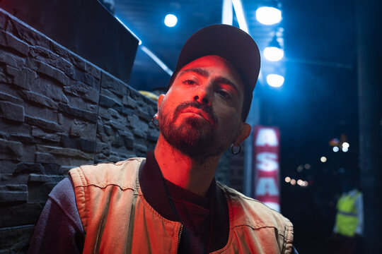 man with beard, hat and earrings looking at camera in the street