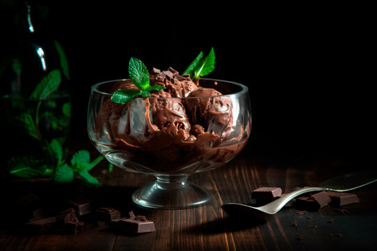Gourmet chocolate ice cream in glass bowl on ice cream parlor table. Rustic wood. AI generated. frozen dessert