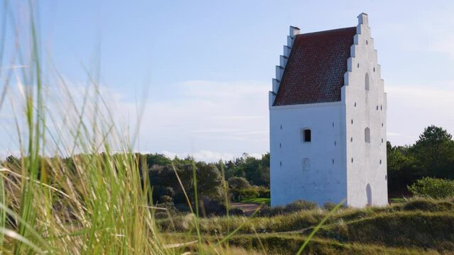 2022 - Tall grass rustles in the wind outside the Den Tilsandede Kirke (the sand-covered church) in Skagen, Denmark on a sunny day.