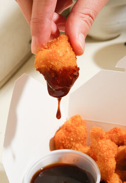 hand dipping nugget in sauce