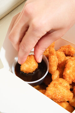 Dipping chicken katsu nuggets in sauce