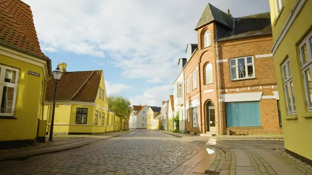 2022 - The sun shines on an intersection of Ribe, Denmark with cobblestone roads.