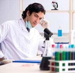 Young handsome chemist working in the lab