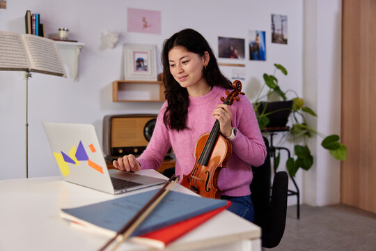 Female violinist preparing for online lesson at home