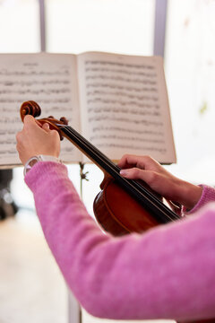 Crop woman preparing violin for rehearsal
