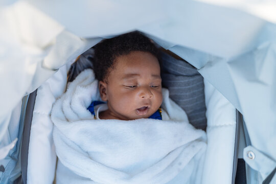 Cute black baby lying in stroller after sleeping