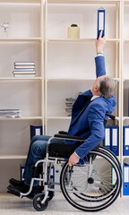 Aged employee in wheelchair working in the office