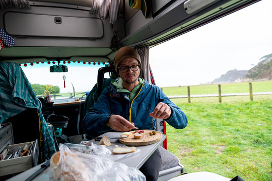 A lonely traveler guy having lunch in camper van by the sea 