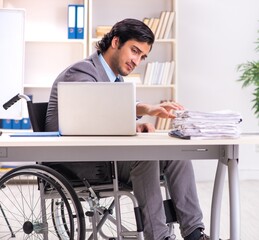 Young handsome employee in wheelchair at the office