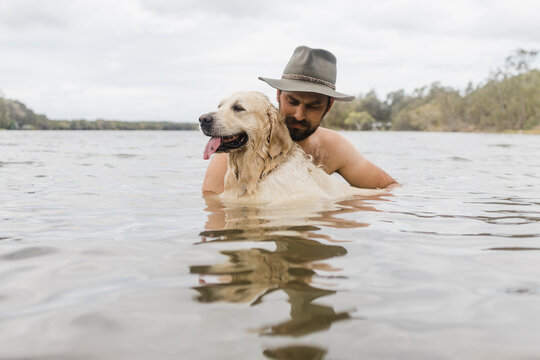 man cuddles dog in water