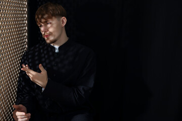 Catholic priest talking to parishioner in confessional. Space for text