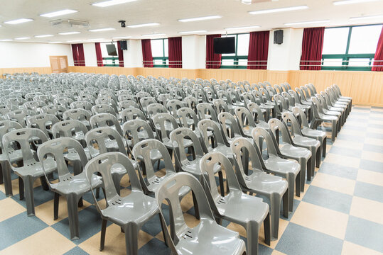 School auditorium with rows of empty plastic chairs