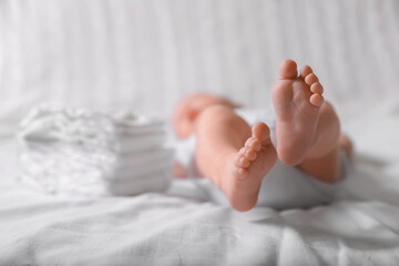 Little baby lying at bed, focus on legs