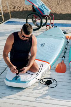 Portrait of an invalid man at the moment of preparing a SUP board