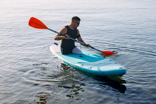A man without legs floats on a Sup board in the early morning 