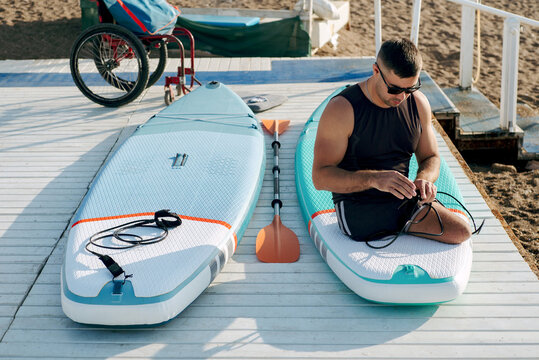 Portrait of an invalid man at the moment of preparing a SUP board