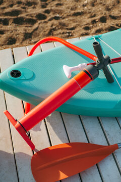 Hand pump lying next to Sup board and paddle
