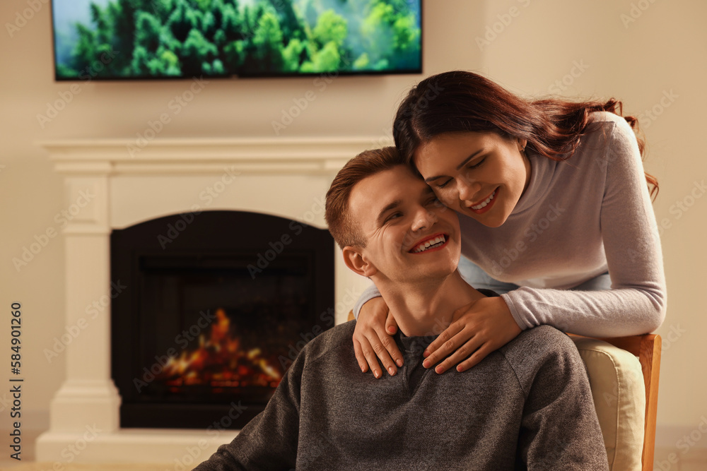 Poster Happy lovely couple spending time together near fireplace at home