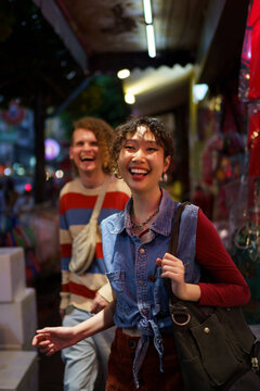 Cheerful friends walking on street in Chinatown at night 