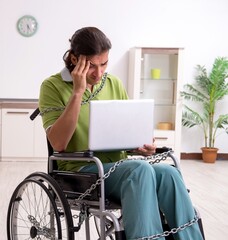 Young male invalid in wheel-chair suffering at home