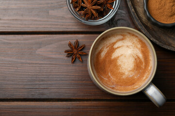 Cup of delicious eggnog with anise on wooden table, flat lay. Space for text