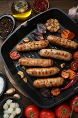 Tasty grilled sausages and ingredients on wooden table, flat lay