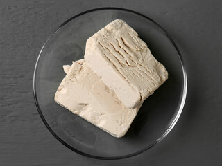 Compressed yeast on grey wooden table, top view