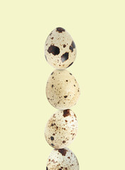Stacked speckled quail eggs on light beige background