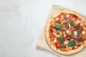 Tasty pizza with anchovies, basil and olives on white table, top view. Space for text