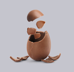 Exploded milk chocolate egg on grey background