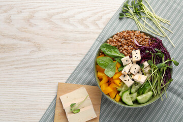 Delicious vegan bowl with bell pepper, tofu and buckwheat on wooden table, top view. Space for text