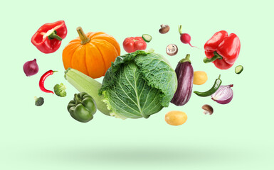 Many different fresh vegetables falling on pale light green background
