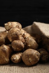 Jerusalem artichokes on bag against dark background, closeup