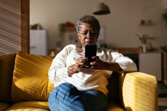Charming senior woman using smartphone at home