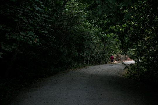 Runner jogging down dark path.