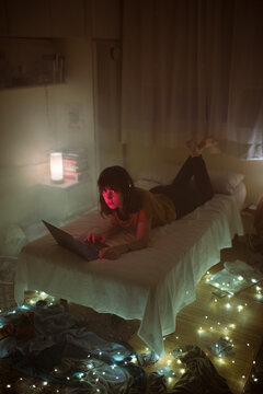 Bored woman using laptop in messy bedroom